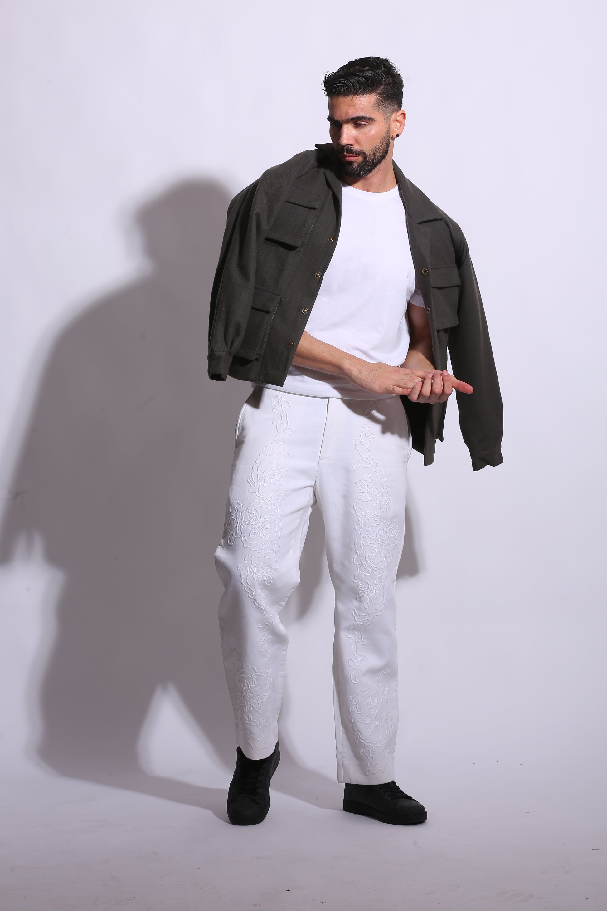 Man wearing a black blazer and white pants on a white background