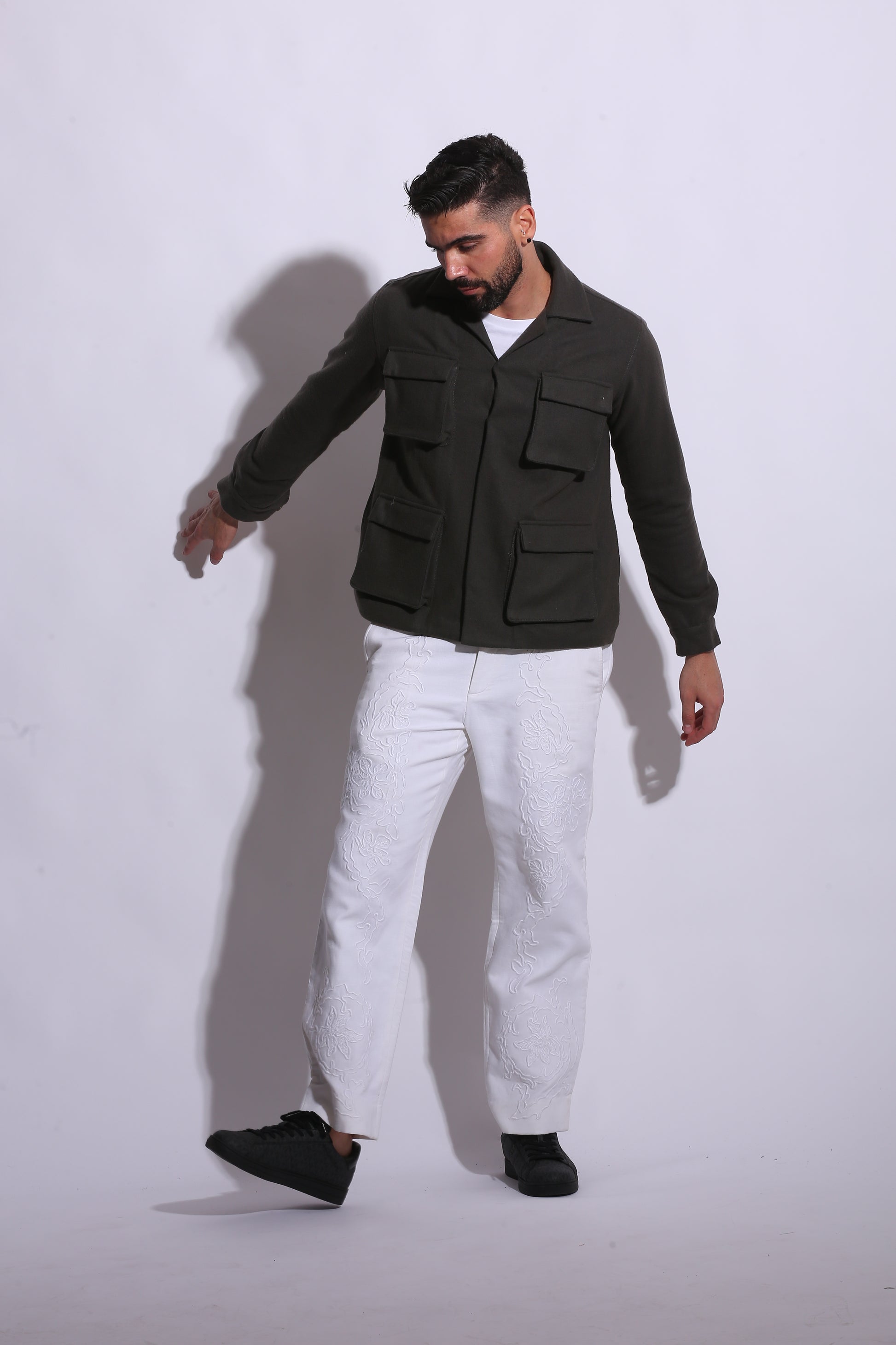 Person wearing a black jacket and white pants on a white background