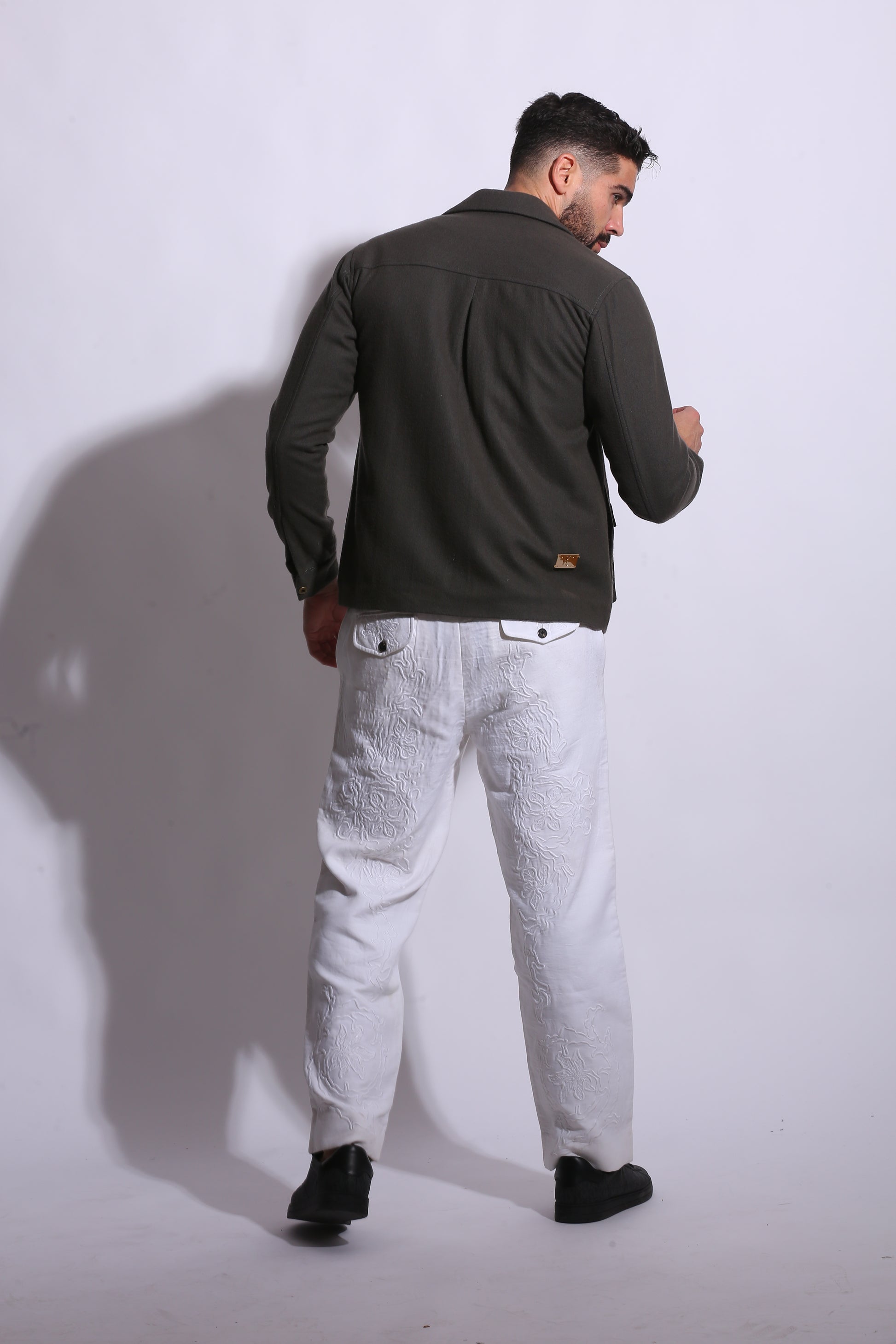 Person wearing a dark jacket and light pants on a white background