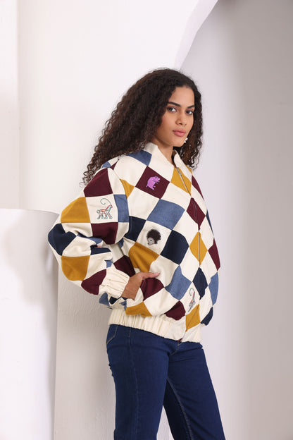A model wearing a multicolored patchwork bomber jacket with geometric patterns, featuring a pinboard on the left side.